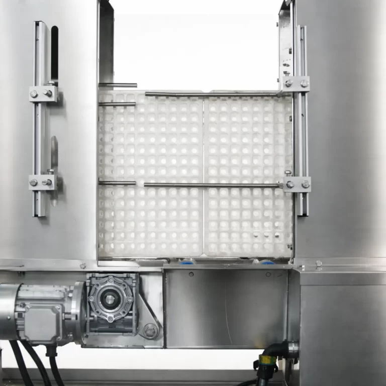 Close-up view of a tray washer cleaning seedling trays inside a stainless steel washing chamber